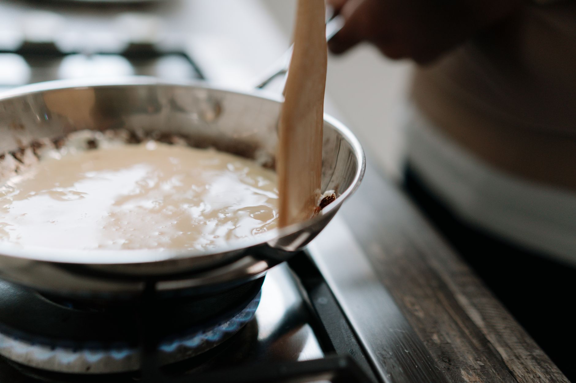 a stainless steel saucepan filled with tomato sauce simmering on a gas stove burner